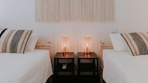Camera da letto con due letti, un pannello decorativo in macramè e lampade da comodino.