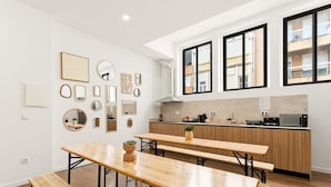 Una cucina moderna con piani di lavoro in legno, piano cottura integrato e forno a microonde. Due finestre assicurano luce naturale.