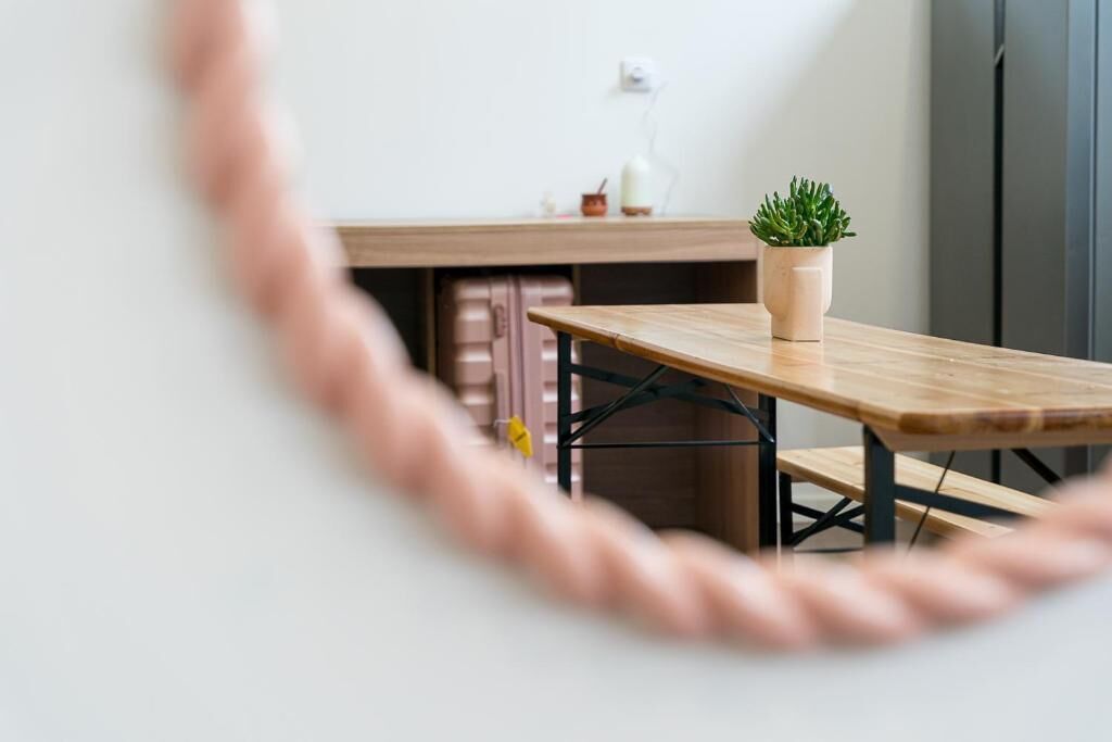 A wooden table with a potted plant, a suitcase, and a wall socket.