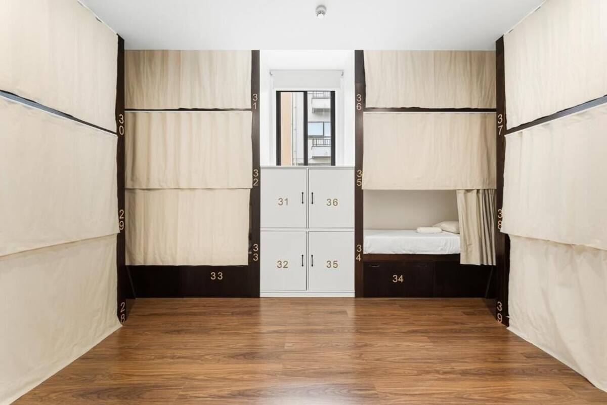 A room with bunk beds, a wardrobe with numbered compartments, and a mirror above the door.