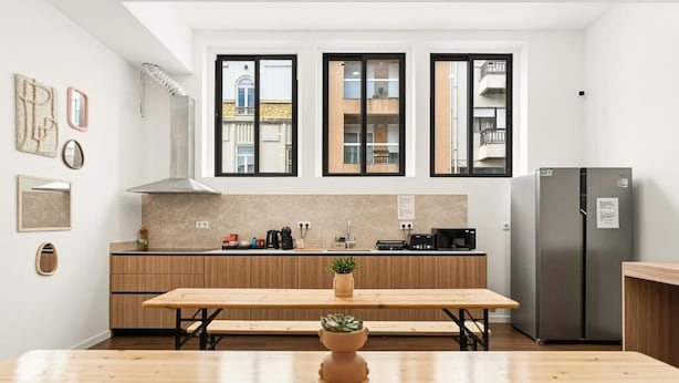 Una cucina moderna con un tavolo di legno, forno a incasso e frigorifero.