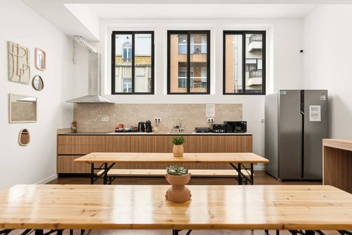 A modern kitchen with a wooden table, a built-in oven, and a refrigerator.