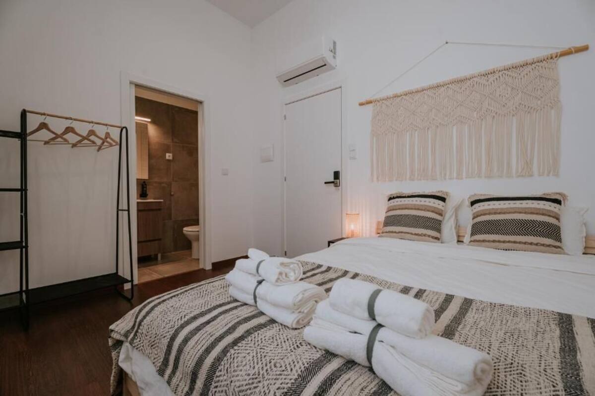 A hotel room with a bed, a wardrobe, a bathroom, and a macrame wall hanging.