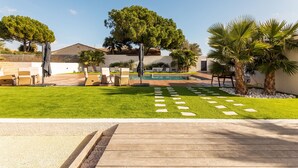 Un espacio exterior cuidado con piscina, terraza de madera y diferentes opciones de descanso.