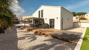 Una casa moderna con un patio, mobiliario exterior y una zona de barbacoa.