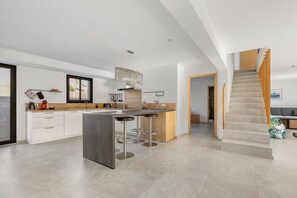 Une cuisine moderne dotée d’un îlot central, de tabourets de bar et d’un escalier menant à un autre niveau.