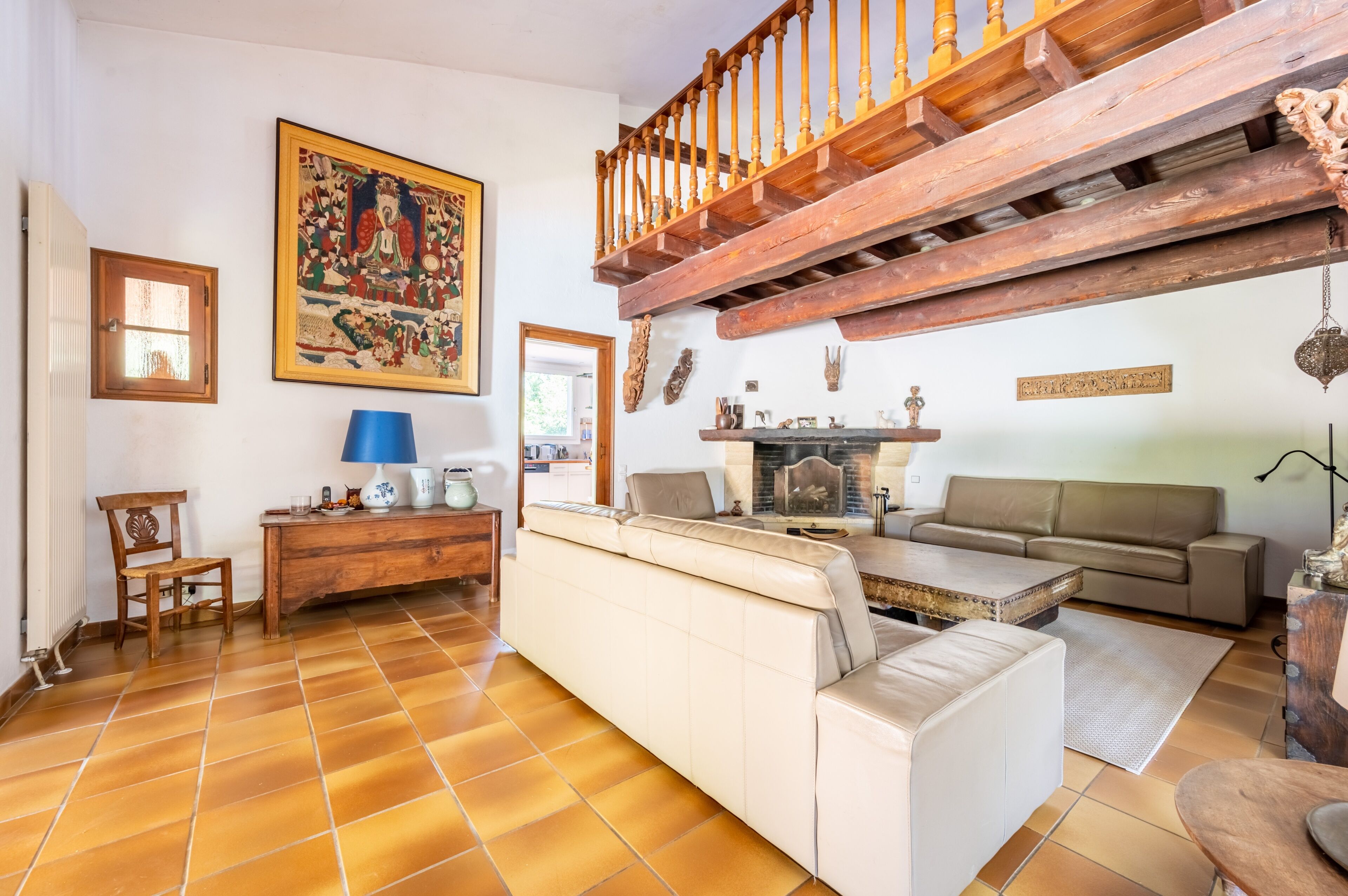 A spacious living room with a high wooden ceiling, a large painting, and a fireplace.