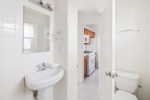 A bathroom with a sink, mirror, and toilet. - Pacific Beach Bungalow - On Boardwalk (San Diego)