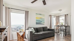 A modern living room with a grey sofa, a wooden coffee table, and a view of the sea through large windows. - Pacific Beach Bungalow - On Boardwalk (San Diego)