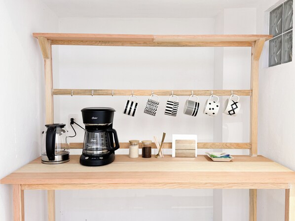 A kitchen area with a coffee maker, hanging mugs, and a wooden shelf. - Casa La Santísima Vista (Tepoztlán)