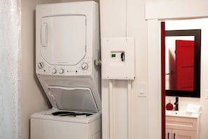A compact laundry room with a front-loading washing machine and a control panel.