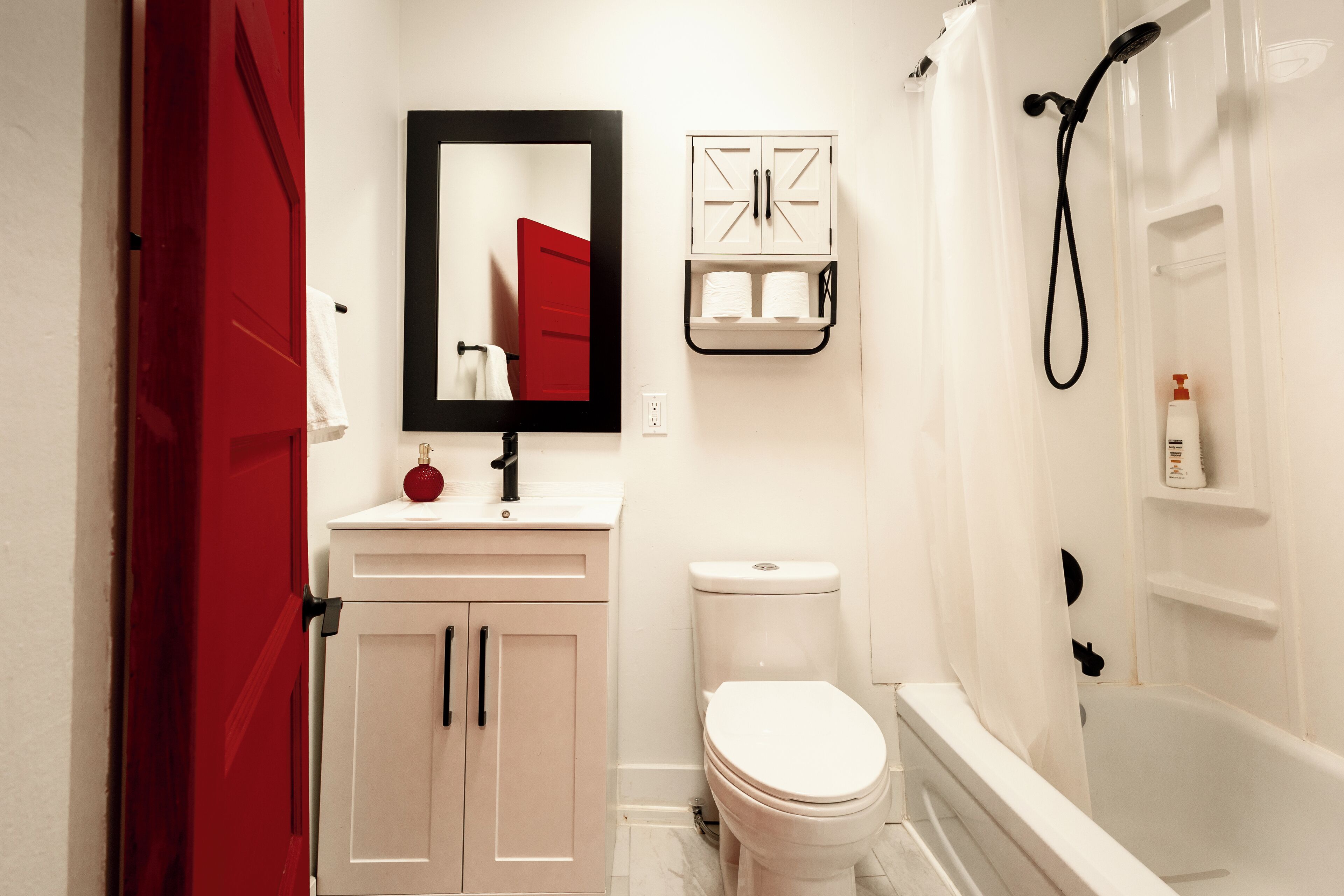 A bathroom with a toilet, sink, mirror, and shower.