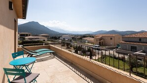 A balcony with a view of a mountain, a tiled floor, and a railing.