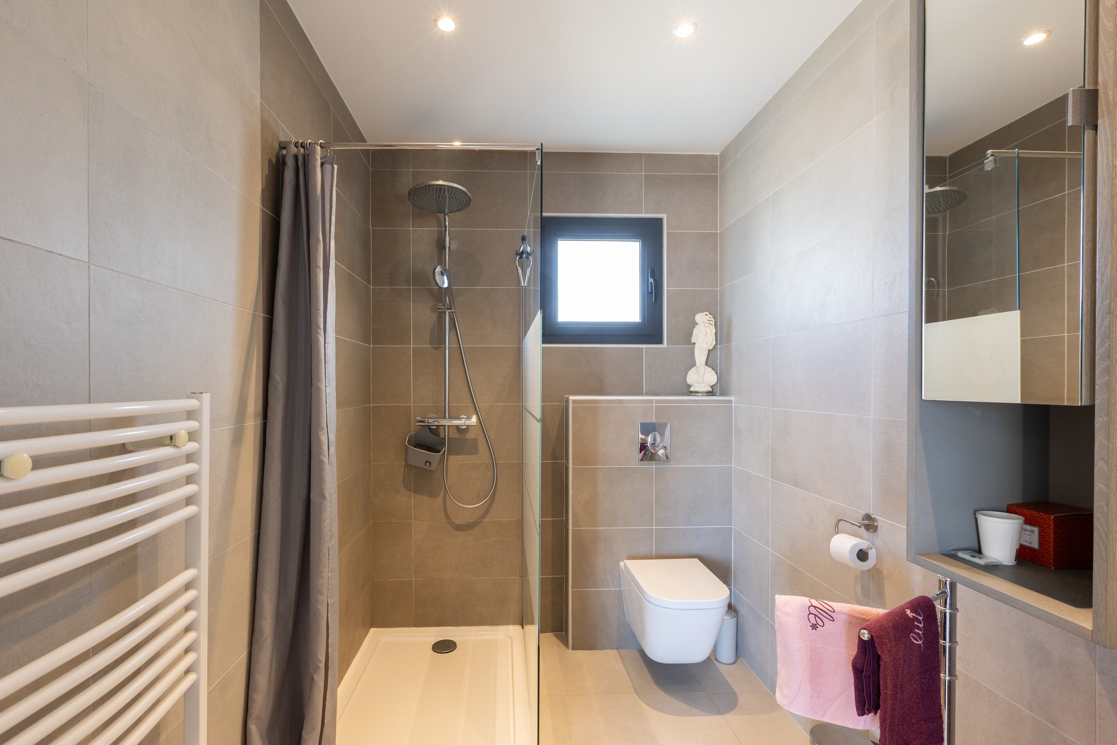 Une salle de bain moderne avec une douche, des toilettes et une petite fenêtre.
