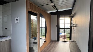 Un intérieur moderne avec un espace cuisine, un lambris en bois et une vue dégagée sur l’extérieur grâce à une grande fenêtre.