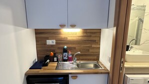 Een compacte keuken met witte kasten, een houten aanrechtblad, een vaatwasser en een wasmachine.