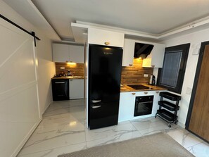 Une cuisine de taille réduite, dotée d’un réfrigérateur noir, d’un four encastré et d’un plan de travail en bois.
