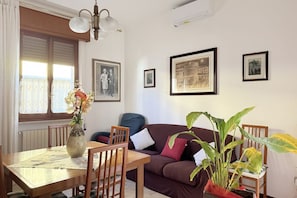 Un coin repas comprenant une table, des chaises, un vase avec des fleurs, un canapé et une plante en pot.