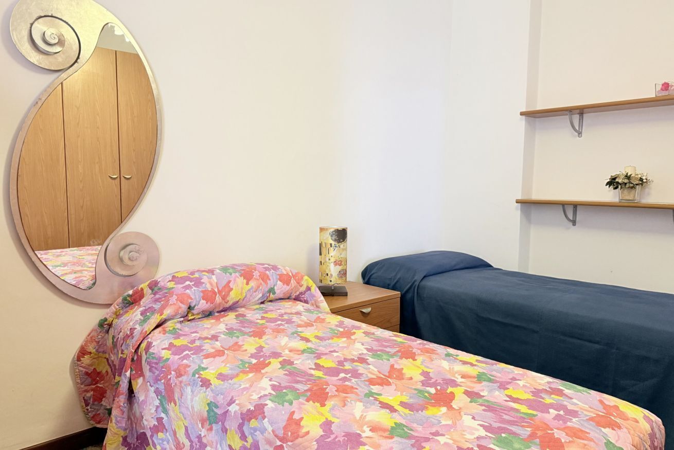 Una camera da letto con un letto, un comodino, uno specchio e una mensola con oggetti decorativi.
