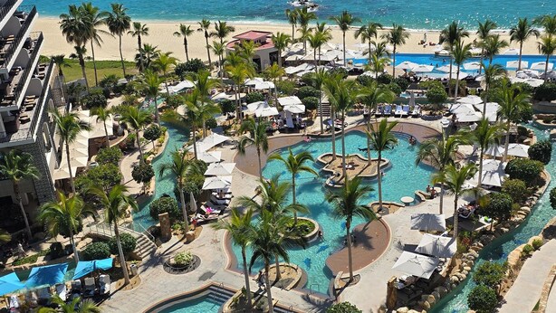 Ein Resort mit mehreren Swimmingpools, Palmen und einem Strandbereich.