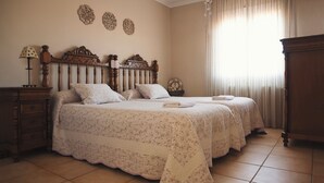A bedroom with two beds, a nightstand, a dresser, and a large window with curtains. - RURAL HOUSE THE WILLOW. 2.5 km from the city of Cuenca. Groups of up to 23 people (Nohales)