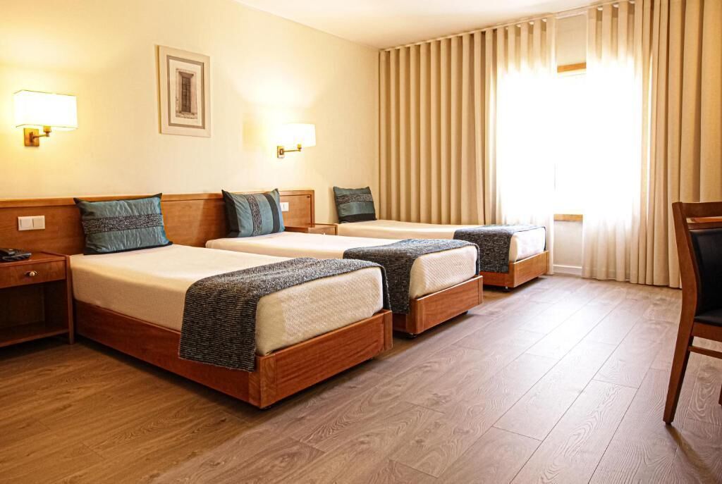 Ein Hotelzimmer mit zwei Betten, einem Schreibtisch und einem Stuhl.