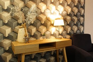 Ein Holzkonsolentisch mit einer Lampe, Dekorationselementen und einer Wand mit geometrischem Muster.