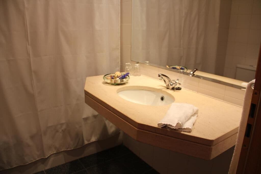 A bathroom with a sink, mirror, and a towel on the counter.