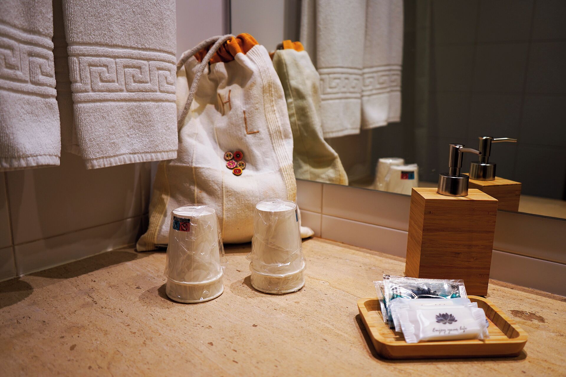 A bathroom with a wooden vanity, a towel rack with patterned towels, and toiletries on the counter.
