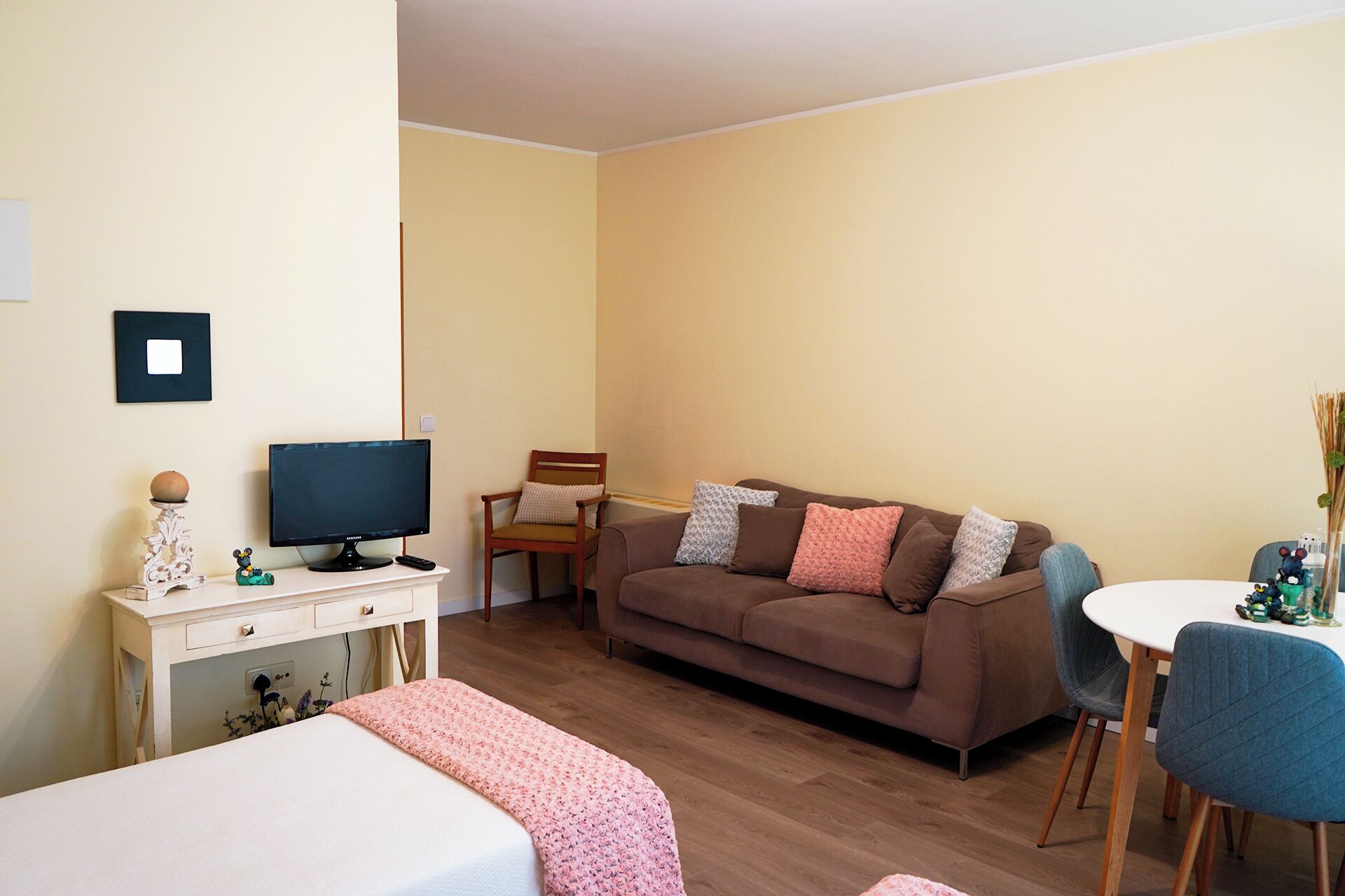 Una sala de estar acogedora con un sofá marrón, un televisor, una mesita y una silla.