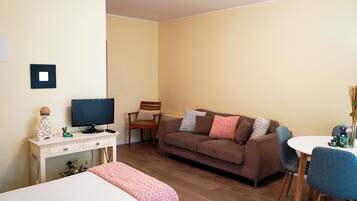 Una sala de estar acogedora con un sofá marrón, un televisor, una mesita y una silla.