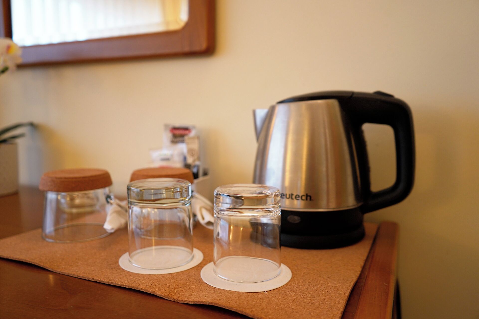 A kitchen counter with a kettle, two glass jars, and a bottle of dish soap.
