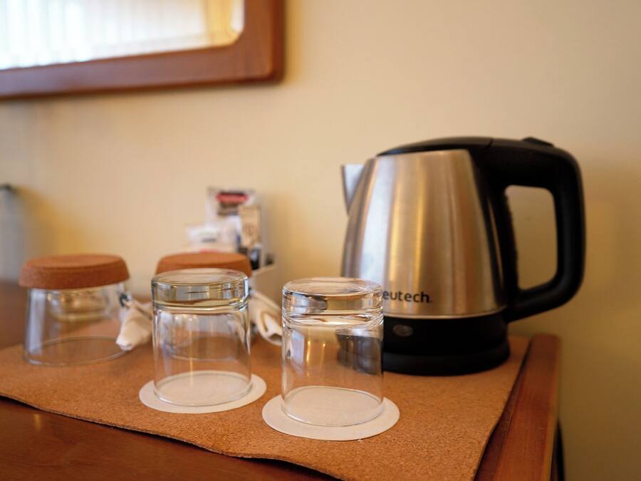 A kitchen counter with a kettle, two glass jars, and a bottle of dish soap.