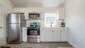 Een moderne keuken met witte kasten, roestvrijstalen apparatuur en een raam.