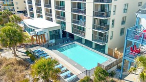 Ett hotell med flera våningar, en pool på taket, balkonger och utomhusområden med sittplatser.