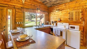 Une cabane en bois dotée d’une cuisine équipée d’une cuisinière, d’un four à micro-ondes et d’un évier.