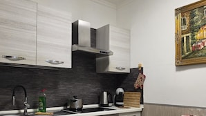 A modern kitchen with a white countertop, stainless steel appliances, and a painting on the wall. - Roomz Romestay (Rome)