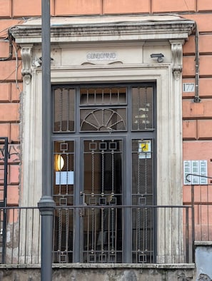 A building facade with a large arched window, a balcony railing, and a plaque reading "CONDOMINIO". - Roomz Romestay (Rome)