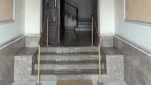 A grand entrance with a marble staircase, a wooden door, and a metal railing. - Roomz Romestay (Rome)