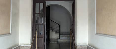 A grand entrance with a marble staircase, a wooden door, and a metal railing.