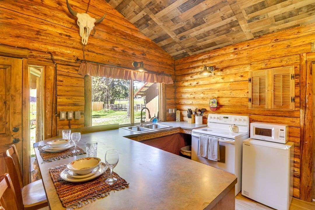 A wooden cabin with a kitchen featuring a stove, microwave, and sink.