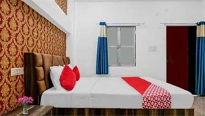 A hotel room with a bed, a nightstand, a window with curtains, and a door. - Hotel O Sant Ravidas Ghat Varanasi (Varanasi)