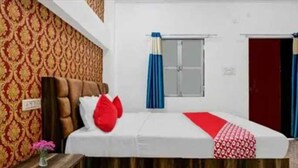 A hotel room with a bed, a window with curtains, a door, and patterned wallpaper. - Hotel O Sant Ravidas Ghat Varanasi (Varanasi)