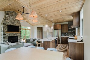 Eine moderne Küche mit Kamin aus Stein, Holzboden und einem Essbereich mit Tisch und Stühlen.