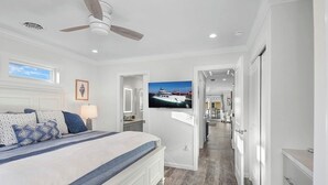 Un dormitorio con cama, ventilador de techo, televisor y vista a un muelle.