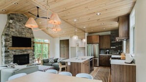 Een moderne keuken met een stenen openhaard, houten plafond en een eethoek met een tafel en stoelen.