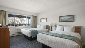 Una habitación de hotel con dos camas, una ventana con cortinas, un radiador, una lámpara y un cuadro en la pared.