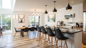 Una cocina moderna con una isla central, taburetes de bar e iluminación colgante.