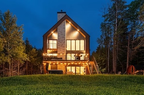 Ein zweistöckiges Holzhaus mit Balkon, umgeben von Bäumen.