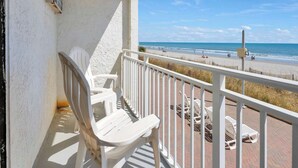 Un balcone con sedie bianche e vista sulla spiaggia.